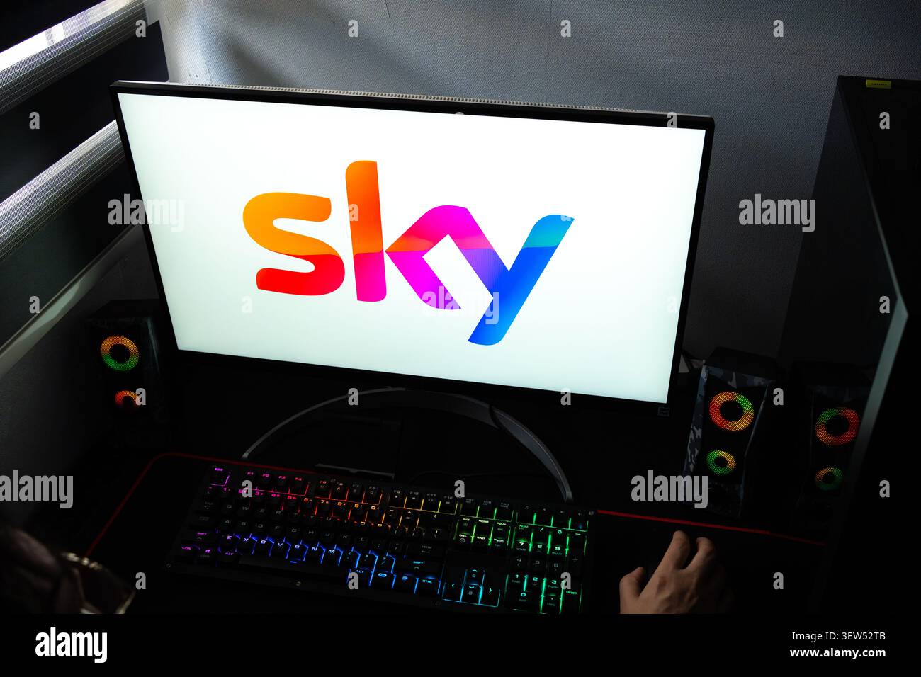 Una persona a una scrivania con il logo del gruppo Sky media e intrattenimento visualizzato su un monitor del computer Foto Stock