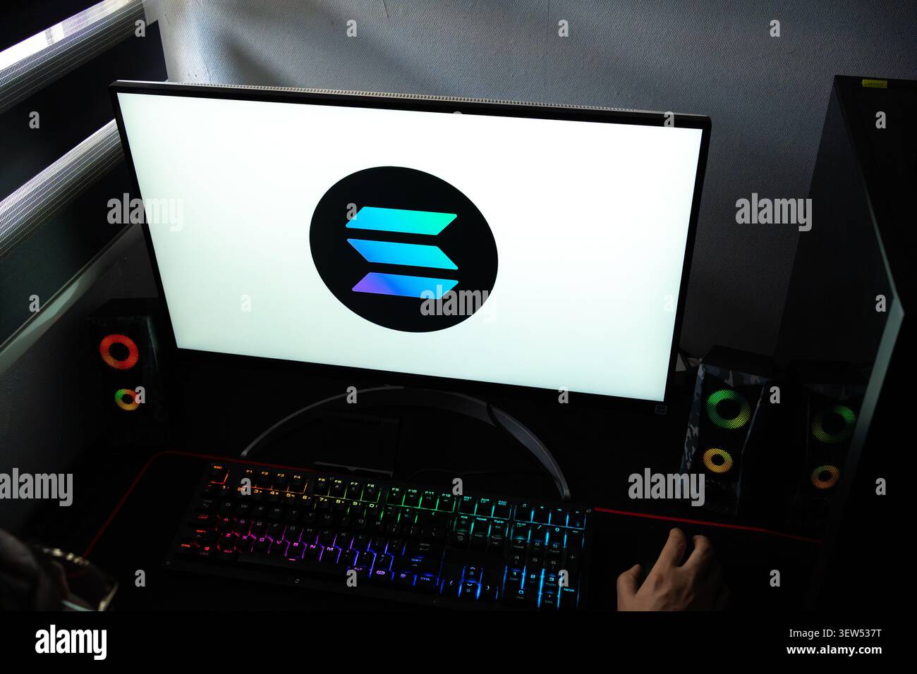 Una persona a una scrivania con il logo Solana (SOL) della blockchain ad alte prestazioni visualizzato su un monitor del computer Foto Stock