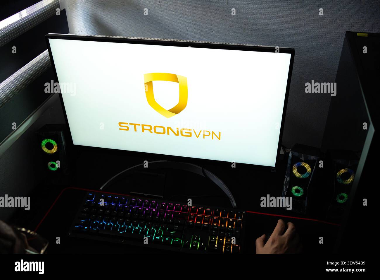 Una persona a una scrivania con il logo di sicurezza e crittografia Internet StrongVPN visualizzato su un monitor del computer Foto Stock