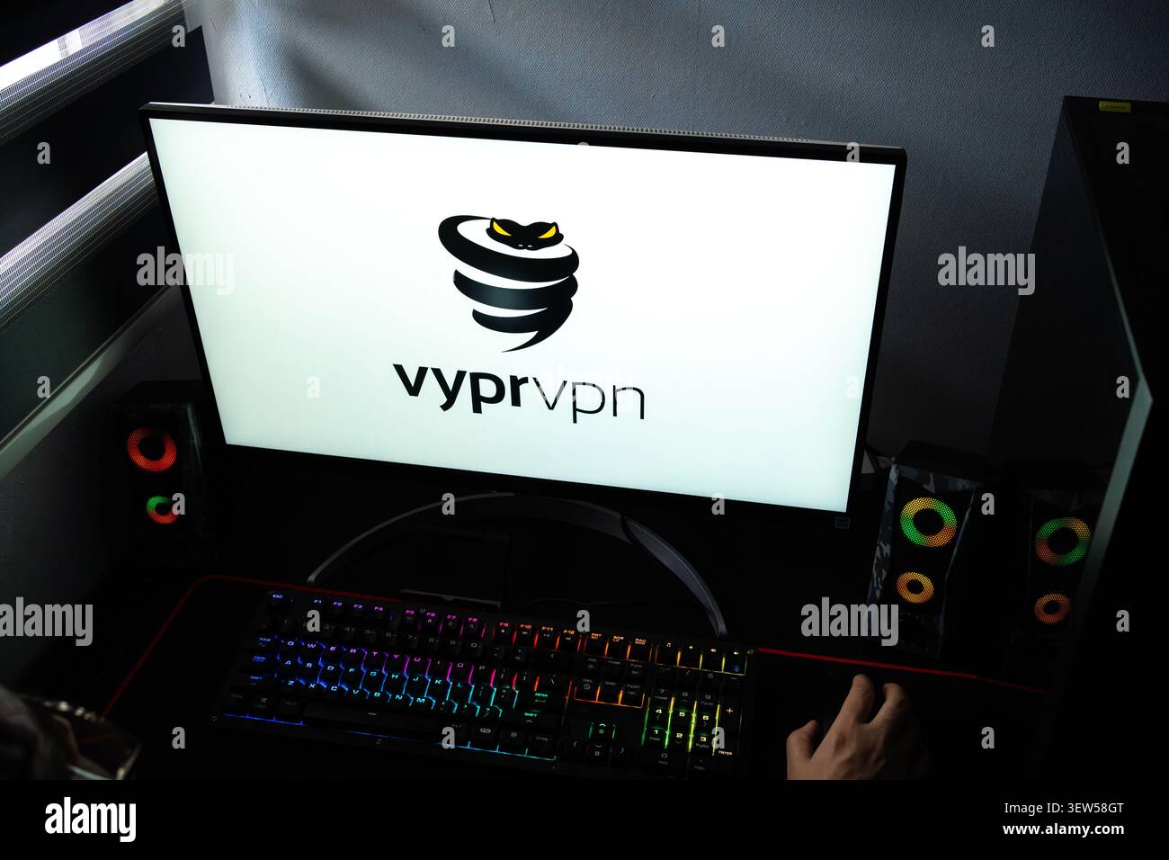 Una persona a una scrivania con il logo VyprVPN per la privacy e la sicurezza su Internet visualizzato su un monitor del computer Foto Stock