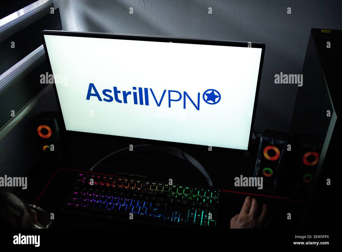 Una persona a una scrivania con il logo aziendale AstrillVPN visualizzato su un monitor del computer Foto Stock