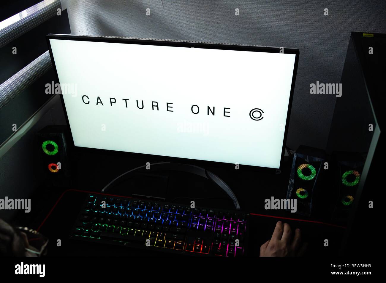 Persona alla scrivania con il logo del software di editing fotografico Capture One visualizzato sul monitor di un computer Foto Stock