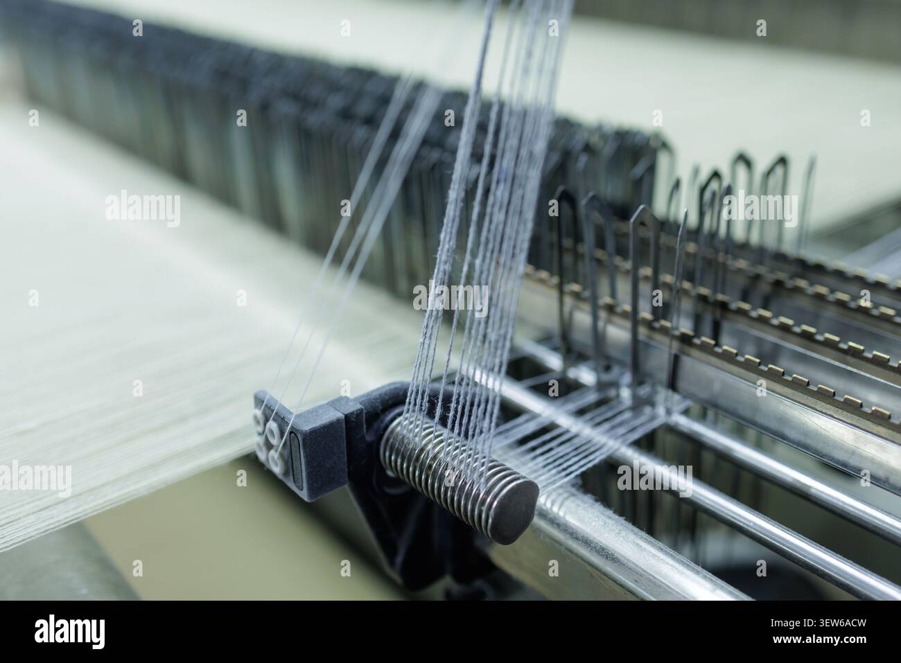 Primo piano di una tessitrice in azione in una fabbrica di produzione di lana, che mostra il processo di filatura e le complesse macchine coinvolte nel manu tessile Foto Stock
