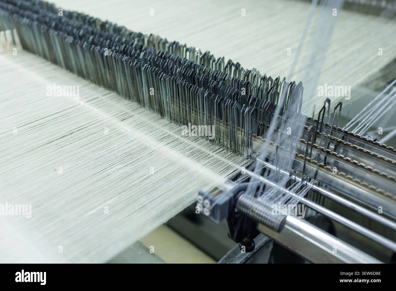 Questa immagine mostra l'intricato processo di produzione della lana in una fabbrica di tessitura, mettendo in evidenza la filatrice e i suoi componenti dettagliati. Foto Stock