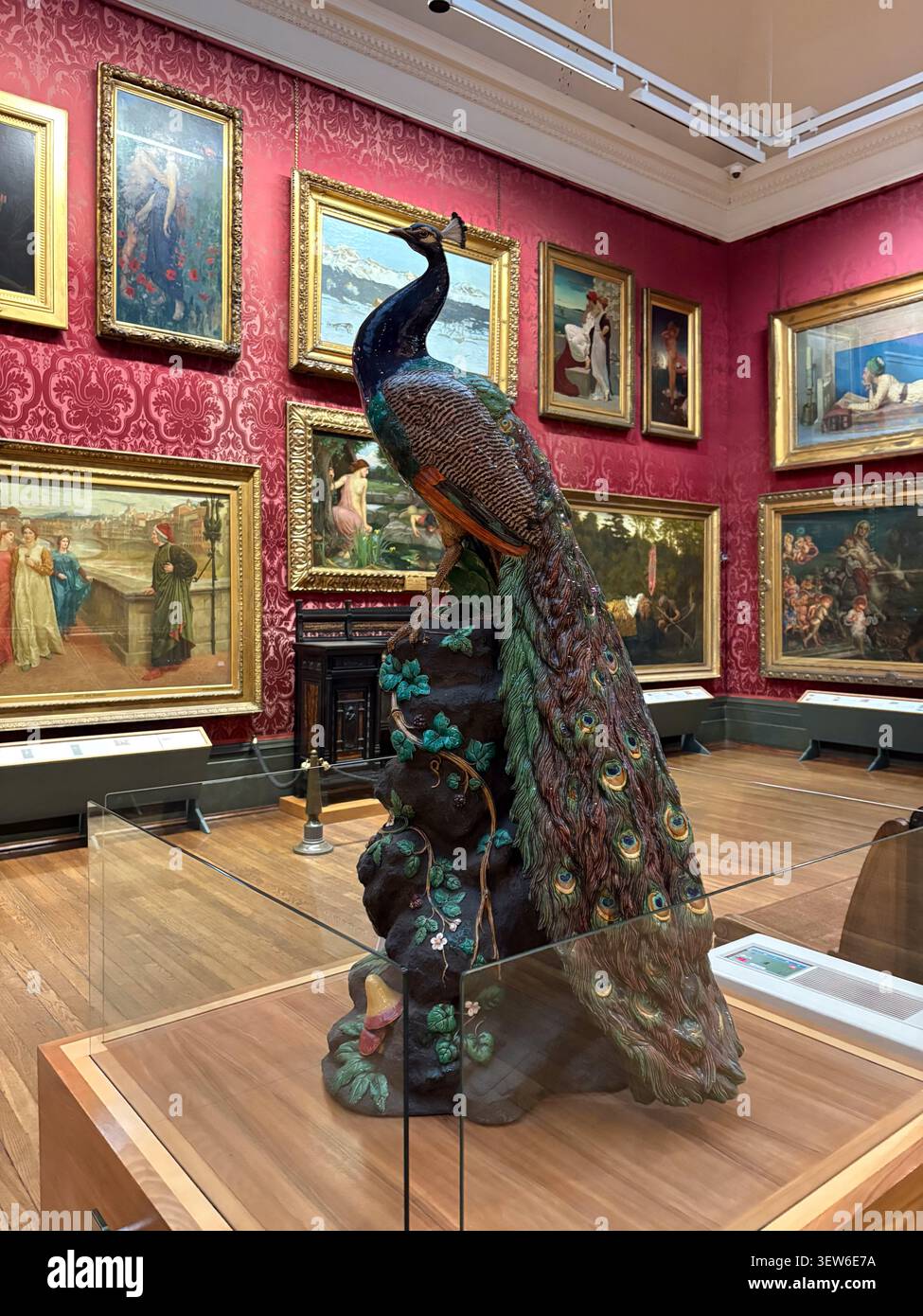 Una scultura decorativa in ceramica pavone esposta nello spazio galleria con pareti rosse della Walker Art Gallery, Liverpool, Inghilterra. Foto Stock