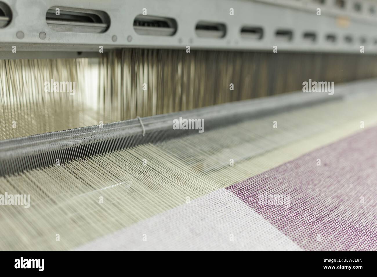 Questa immagine cattura l'intricato processo di tessitura in una fabbrica di produzione di lana, mostrando la filatrice in azione per la produzione tessile Foto Stock