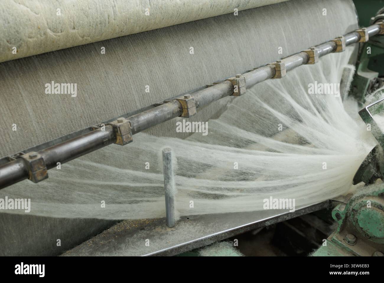 Una panoramica dettagliata del processo di produzione della lana Merino, che mostra i macchinari utilizzati per la filatura e la cardatura della lana grezza in filati fini. Foto Stock