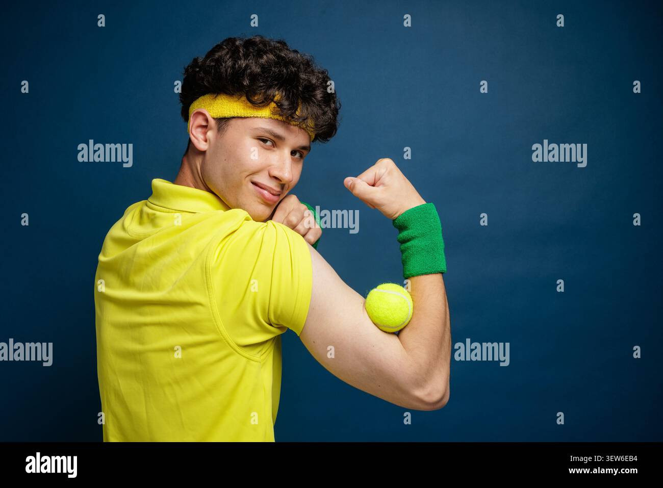 Un tennista allegro si flette con una palla da tennis, mostrando vittoria ed emozioni, ideale per allenamenti, allenamenti o educazione sportiva Foto Stock