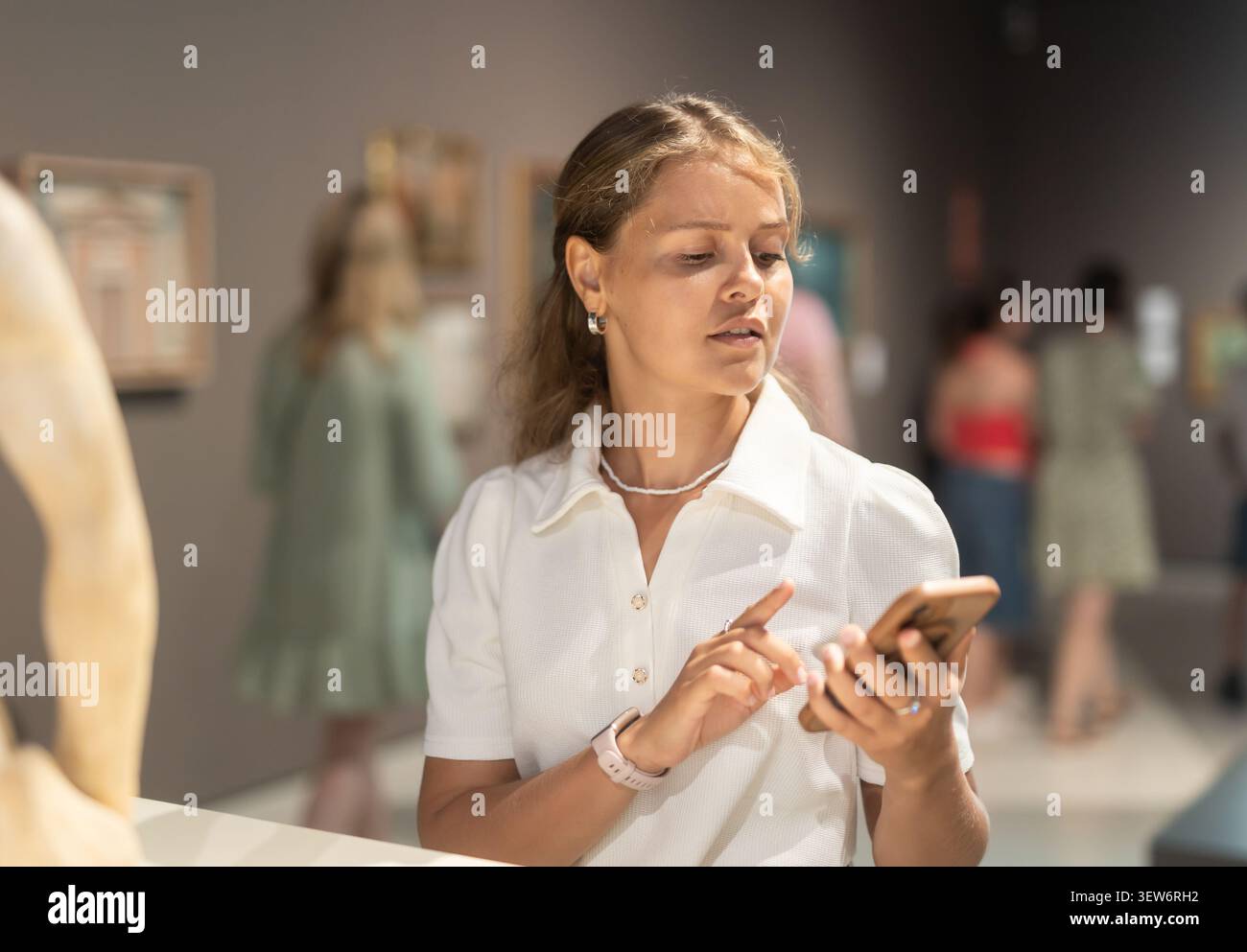 Una ragazza con il telefono in mano cammina per la sala del museo e guarda gli oggetti della mostra Foto Stock