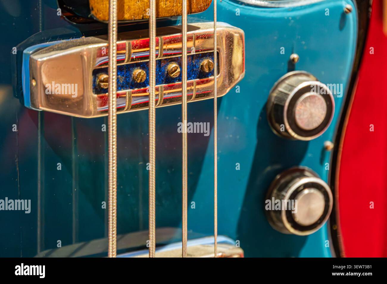 Primo piano di una chitarra elettrica vintage, con testa in acero lucido, piedini di sintonizzazione metallici, vivace finitura turchese del corpo, condizioni ben mantenute, Foto Stock