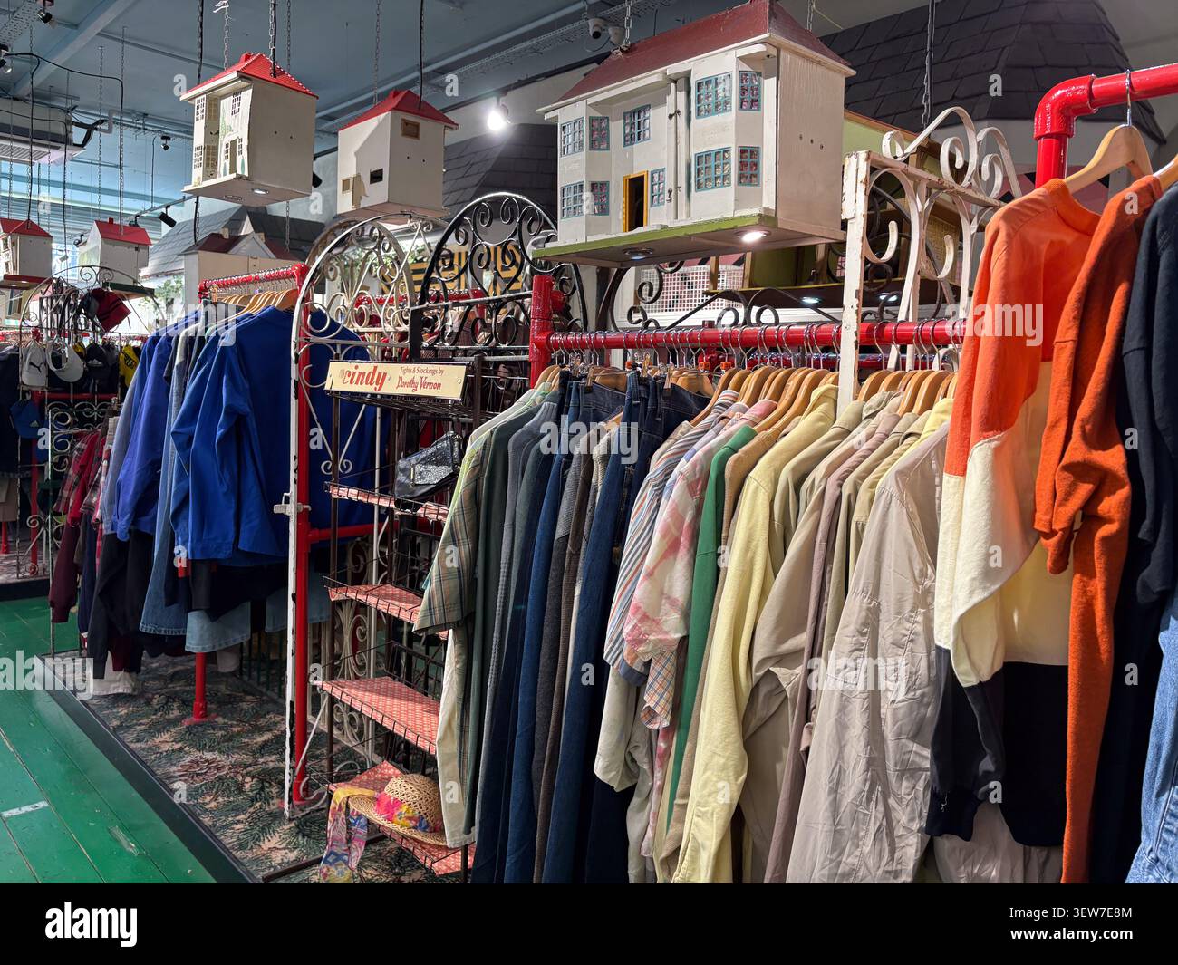 Abbigliamento vintage assortito su rotaie all'interno di un negozio a Bold Street, Liverpool, Regno Unito, con case modello appese come arredamento interno. Foto Stock