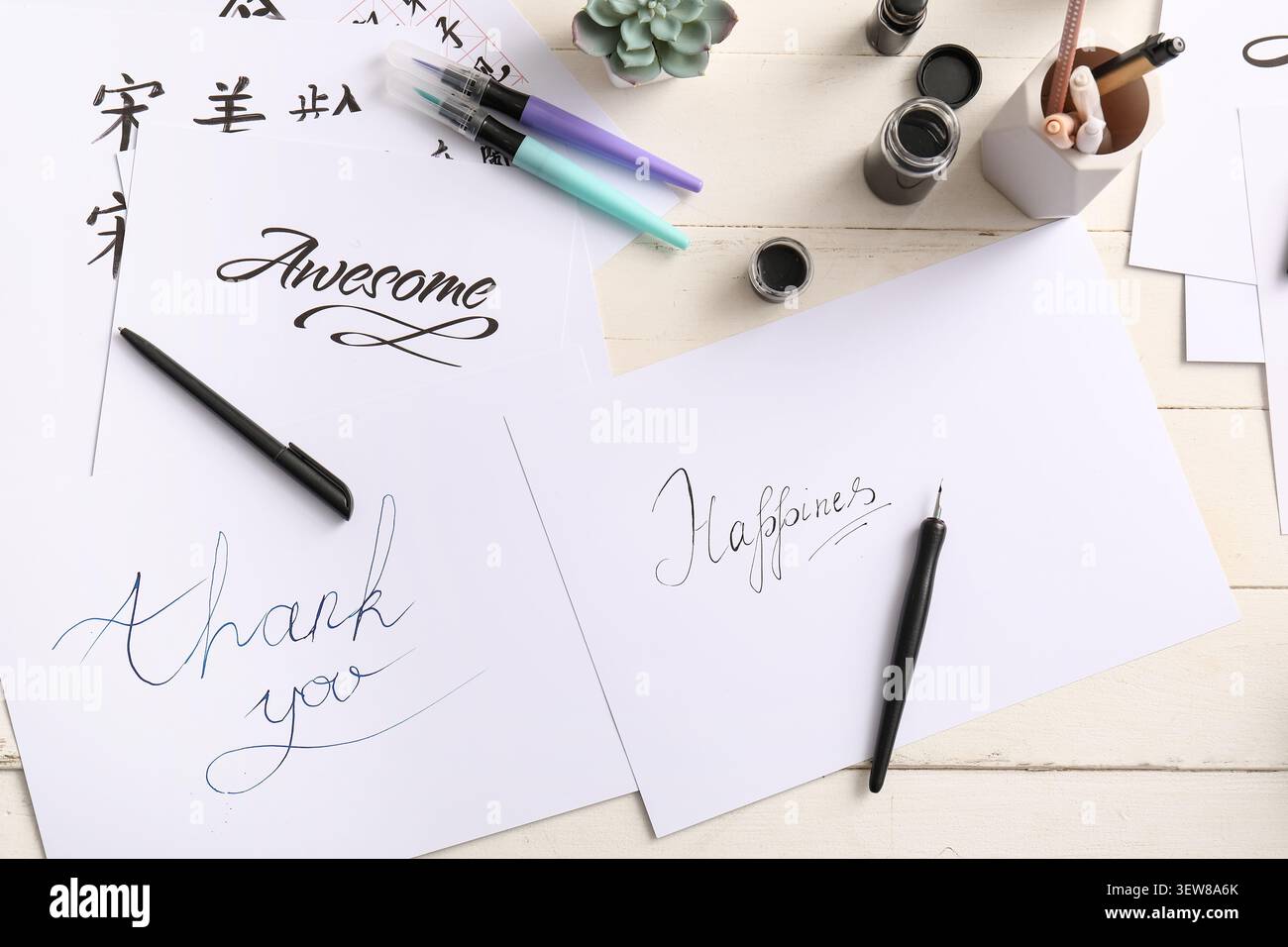 Pratica calligrafica con parole positive e strumenti di scrittura Foto Stock