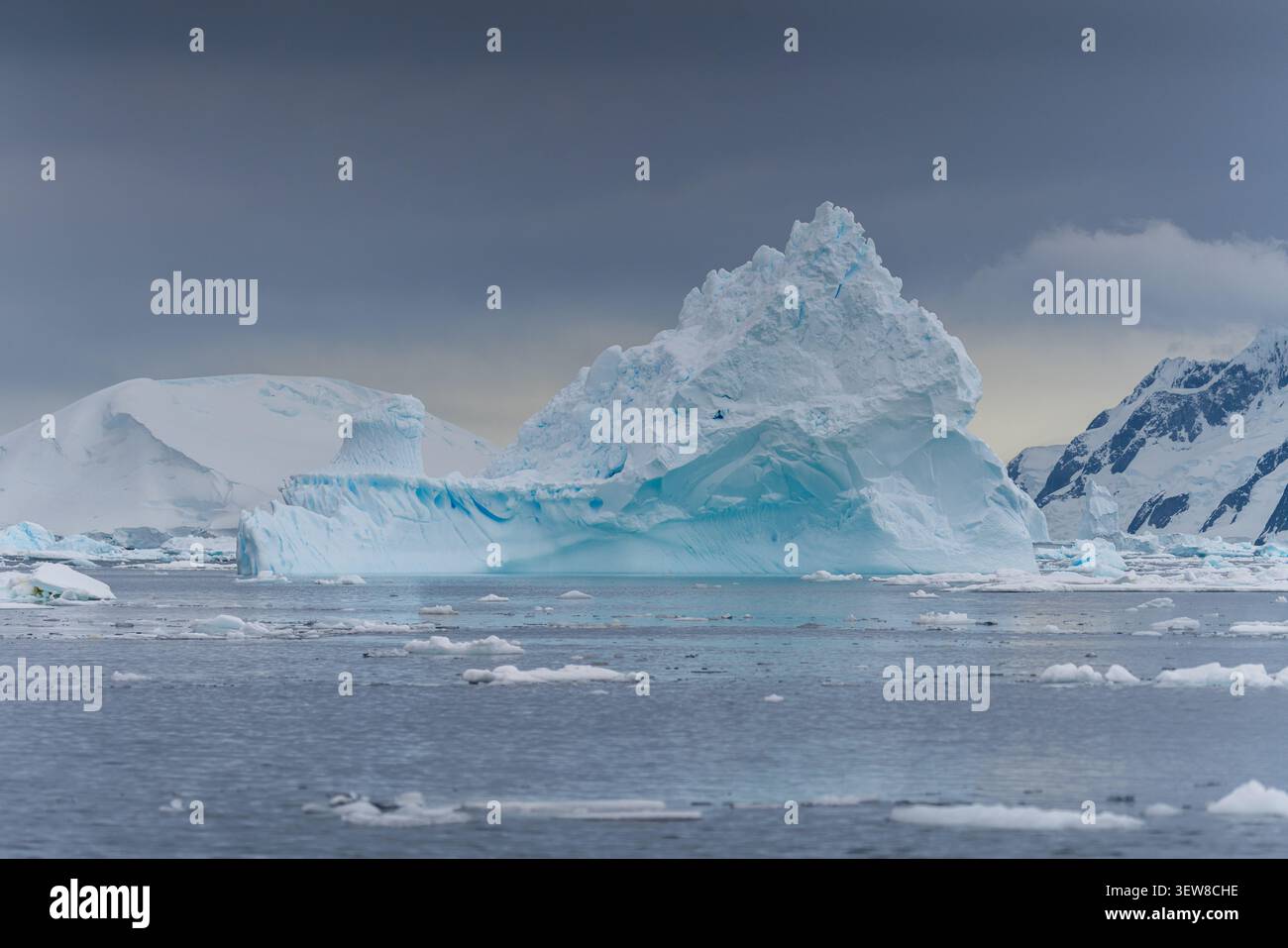 Un suggestivo iceberg blu che galleggia nelle acque ghiacciate della Penisola Antartica sotto le spettacolari nuvole di tempesta Foto Stock