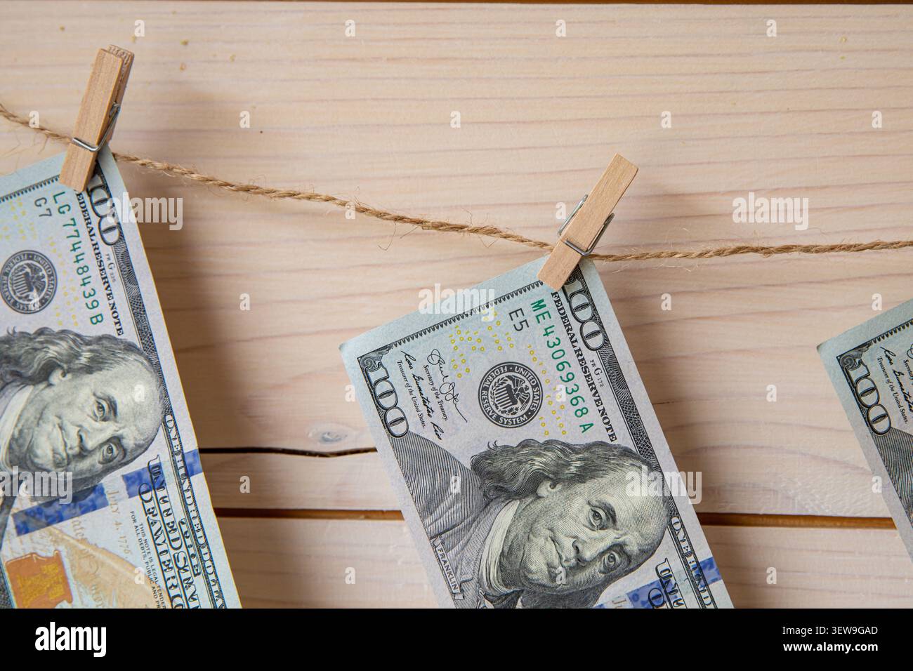 Banconote in dollari USA appese su una clothesline con clothespins su sfondo di legno Foto Stock