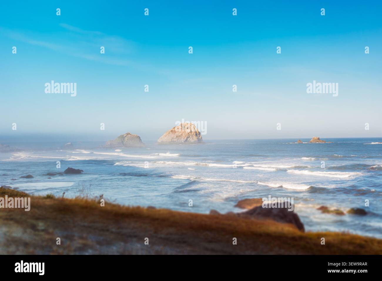 I fondali marini illuminati dal sole si innalzano da un orizzonte oceanico nebbioso Foto Stock