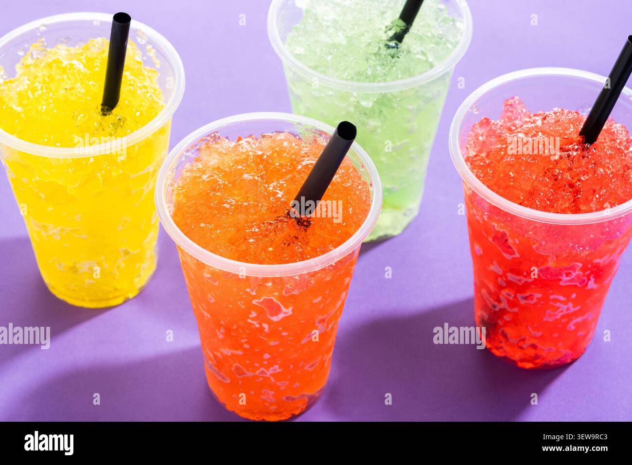 Colorate bibite ghiacciate in tazze di plastica su sfondo viola Foto Stock