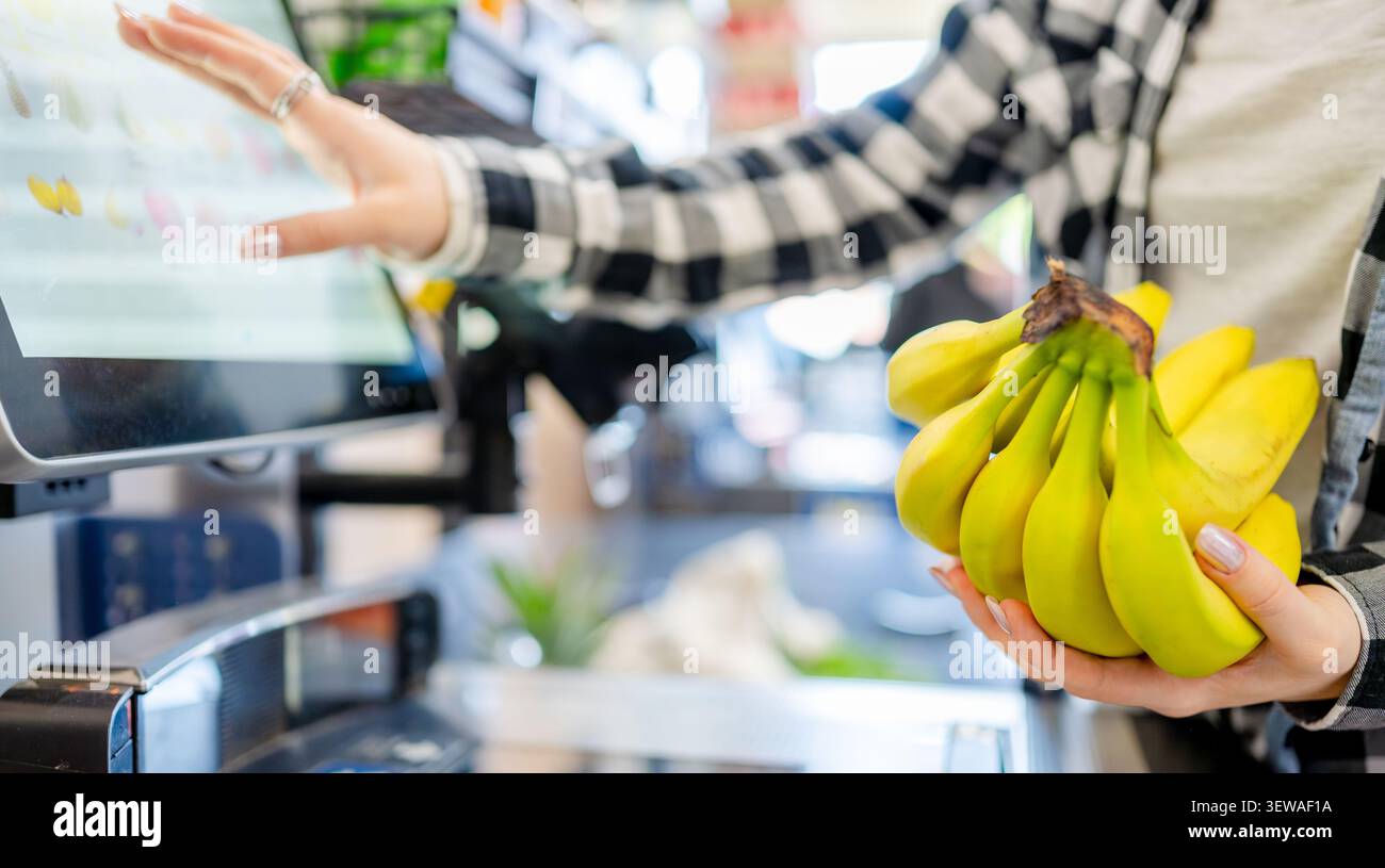 Ragazza al Self-Checkout che scansiona oggetti e banane Foto Stock