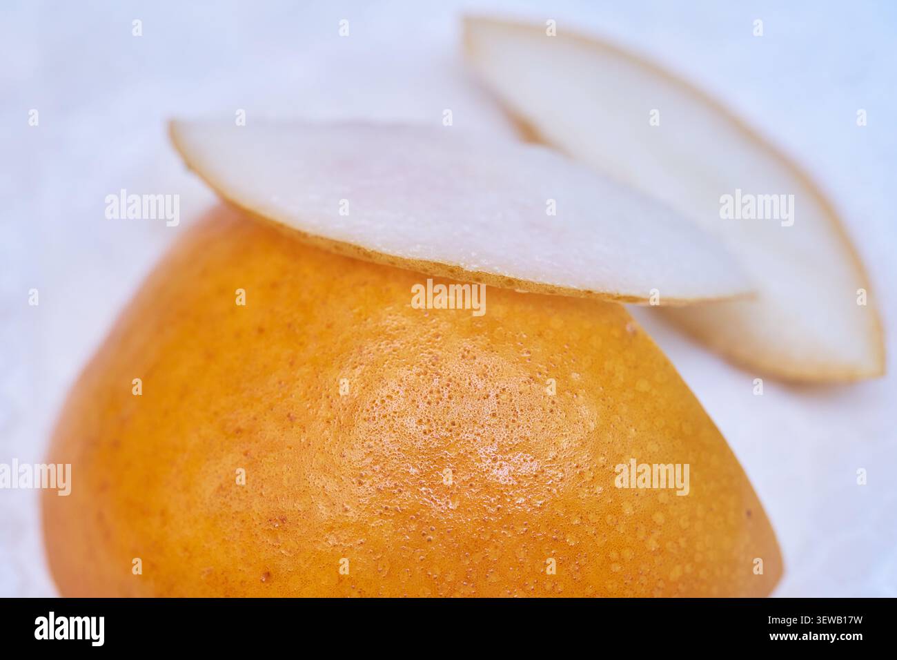 Macro shot di una pera asiatica a fette con pelle dorata intatta che enfatizza l'agricoltura biologica e i benefici nutrizionali di mangiare frutta cruda non sbucciata Foto Stock
