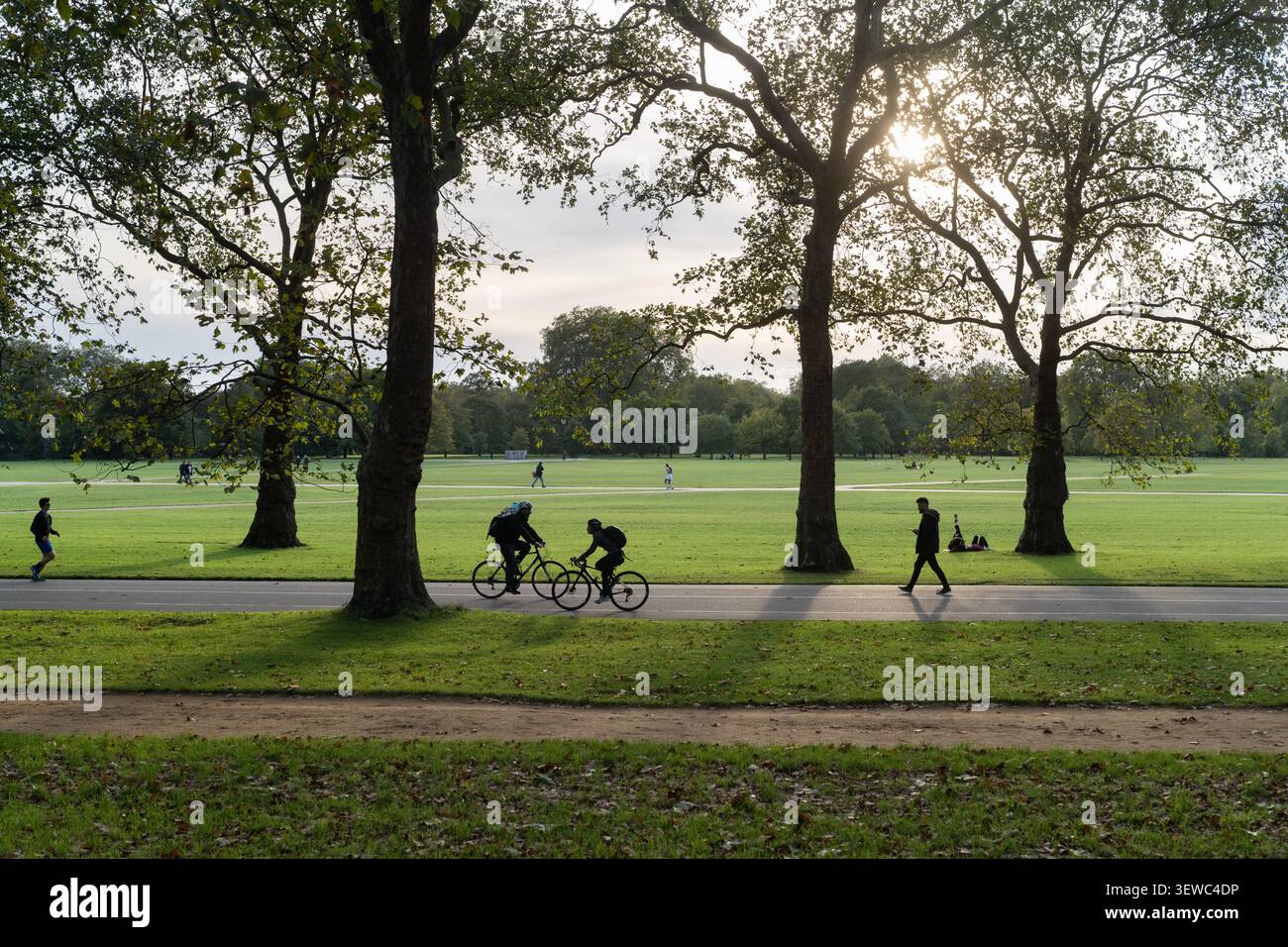 Le persone pedalano, corrono e camminano per fare esercizio fisico attraverso i sentieri panoramici di Hyde Park, un famoso punto di riferimento verde nel centro di Londra. Foto Stock
