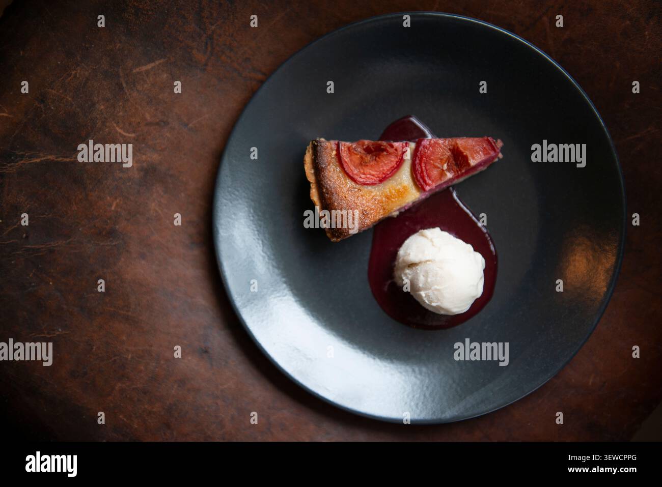Delizioso dessert Scomponi su un piatto nero con un gelato cremoso accanto Foto Stock