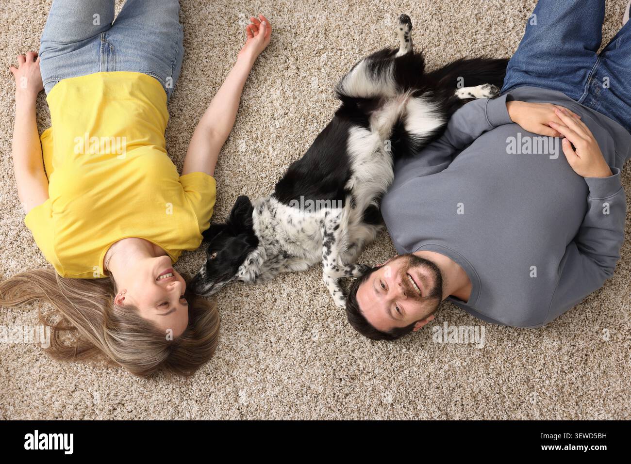 Una coppia felice e il loro cane sdraiati sul pavimento, vista dall'alto Foto Stock