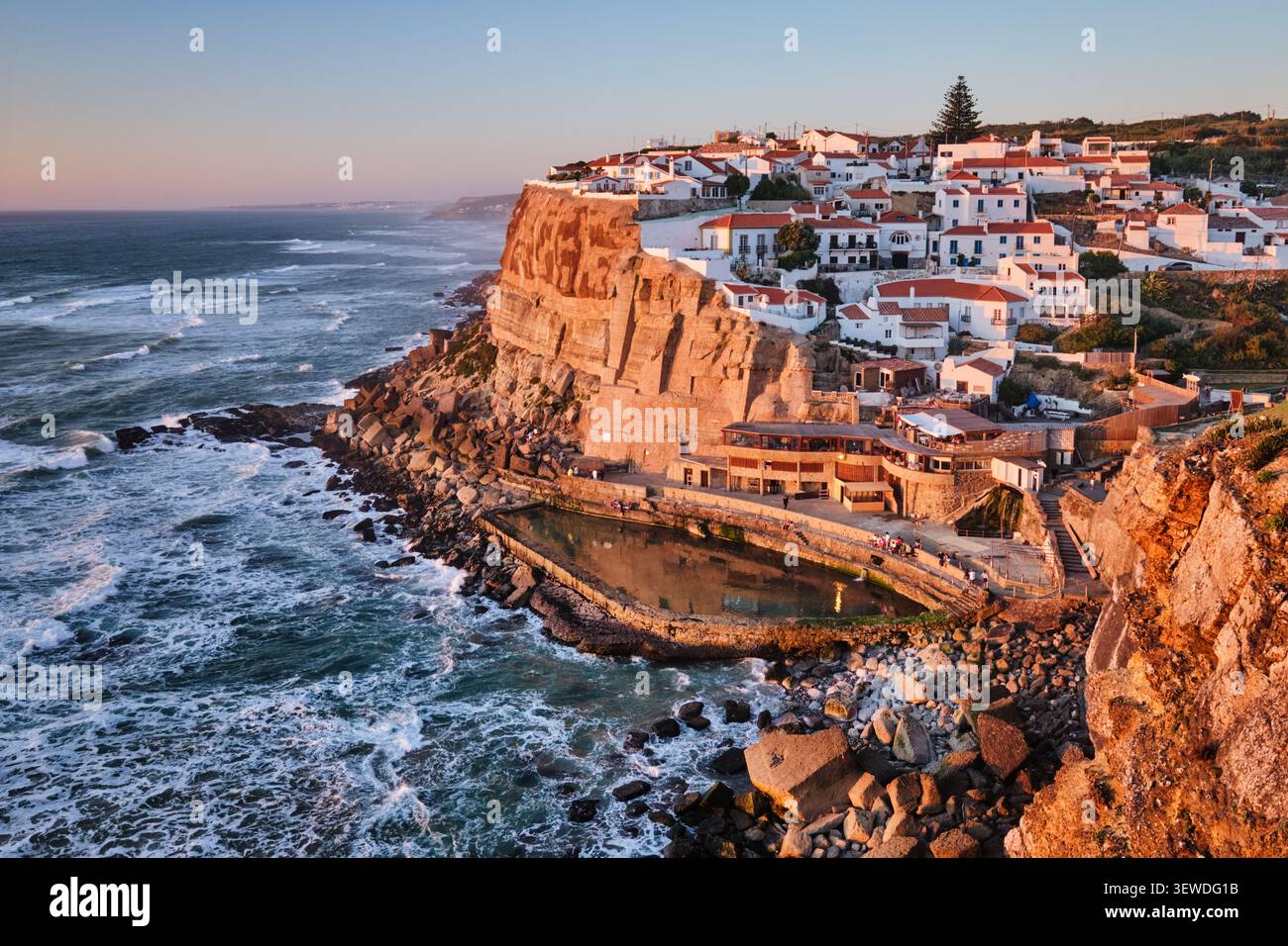 Vista mozzafiato di Azenhas do Mar, un affascinante villaggio sul mare arroccato sulle scogliere dell'oceano Atlantico. I colori caldi del tramonto evidenziano il pictu Foto Stock