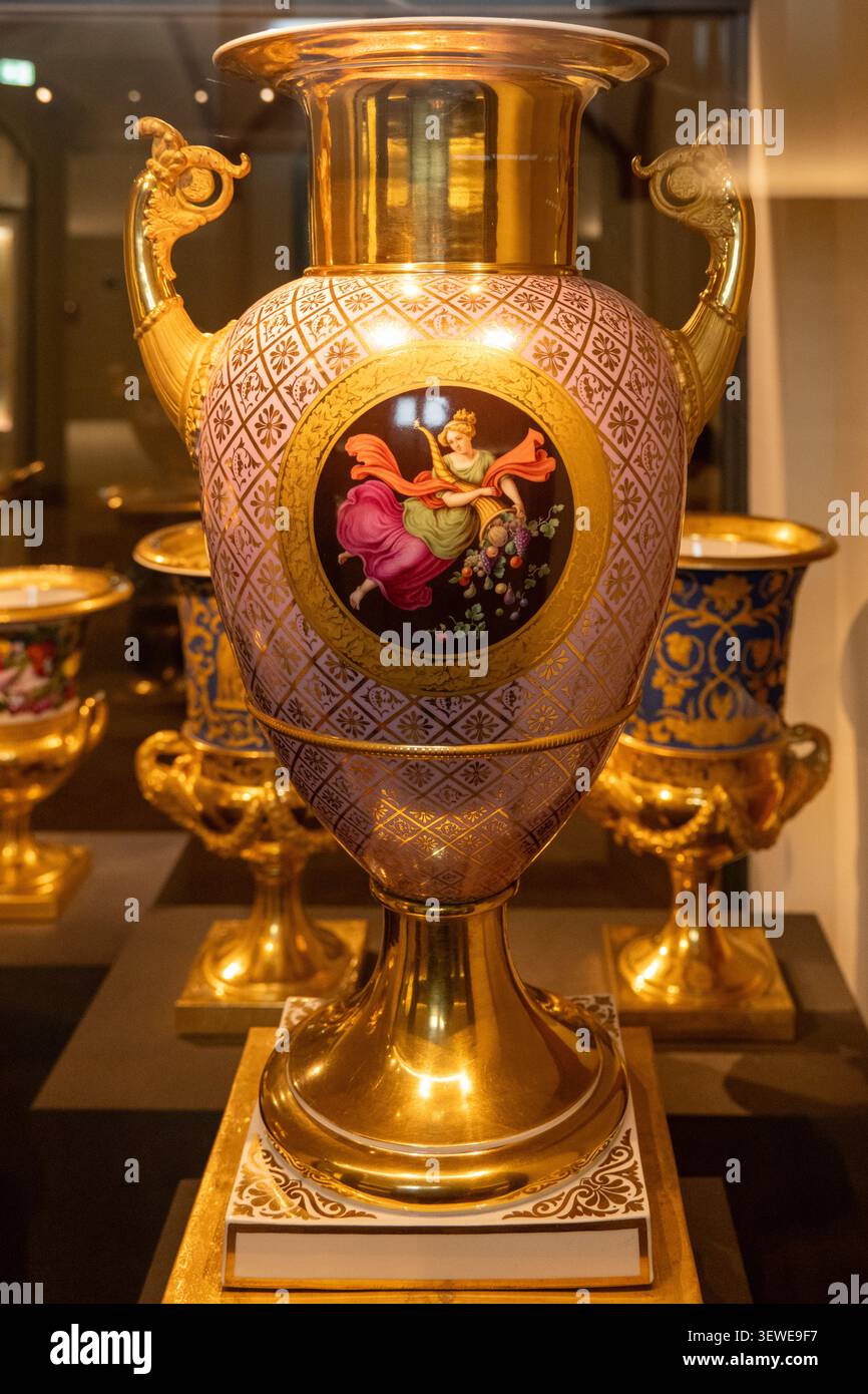 Schweren, Germania - 6 aprile 25: Vaso in porcellana dorata ornata con manici e medaglione dipinto, fotografato in una mostra museale al castello di Schwerin in Foto Stock