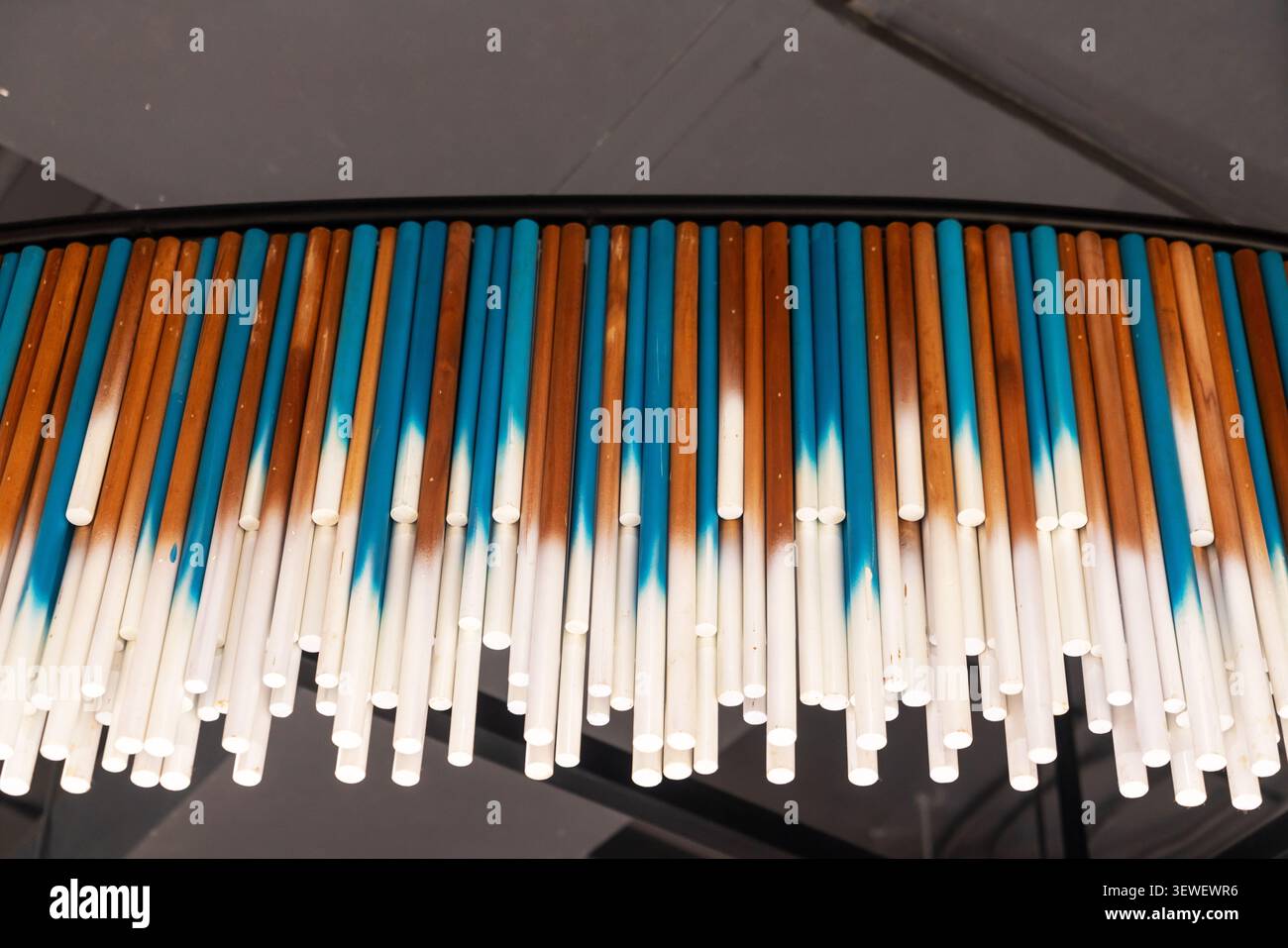 Un'accattivante esposizione di cannucce colorate disposte in un motivo a righe con sfumature arancione, blu e bianco, che mostrano una vivace, moderna, e arte Foto Stock
