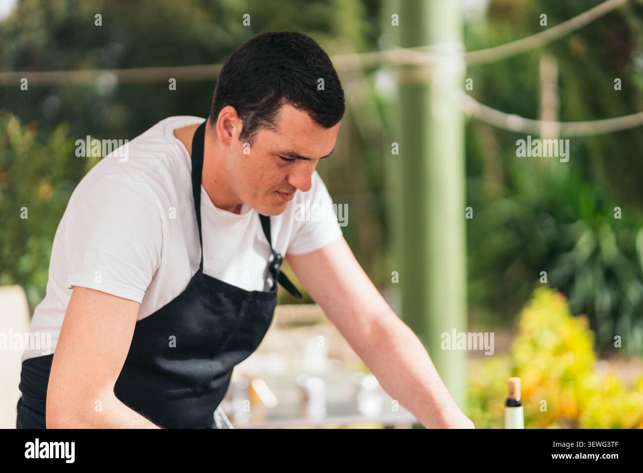 Grembiule da cuoco uomo che si concentra sulla creazione di cibo culinario all'aperto Foto Stock