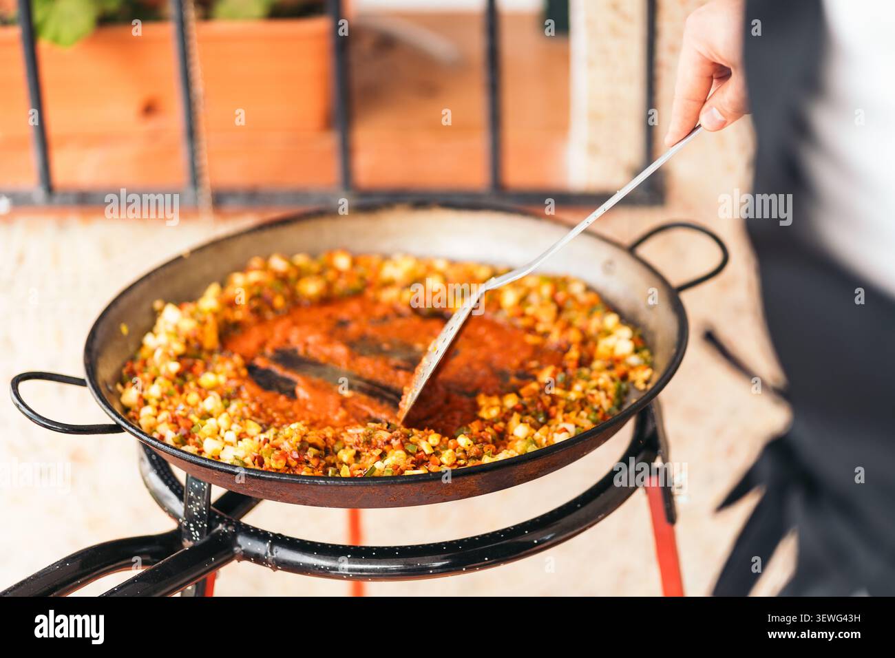 Lo chef mescola gli ingredienti in una paella grande Foto Stock