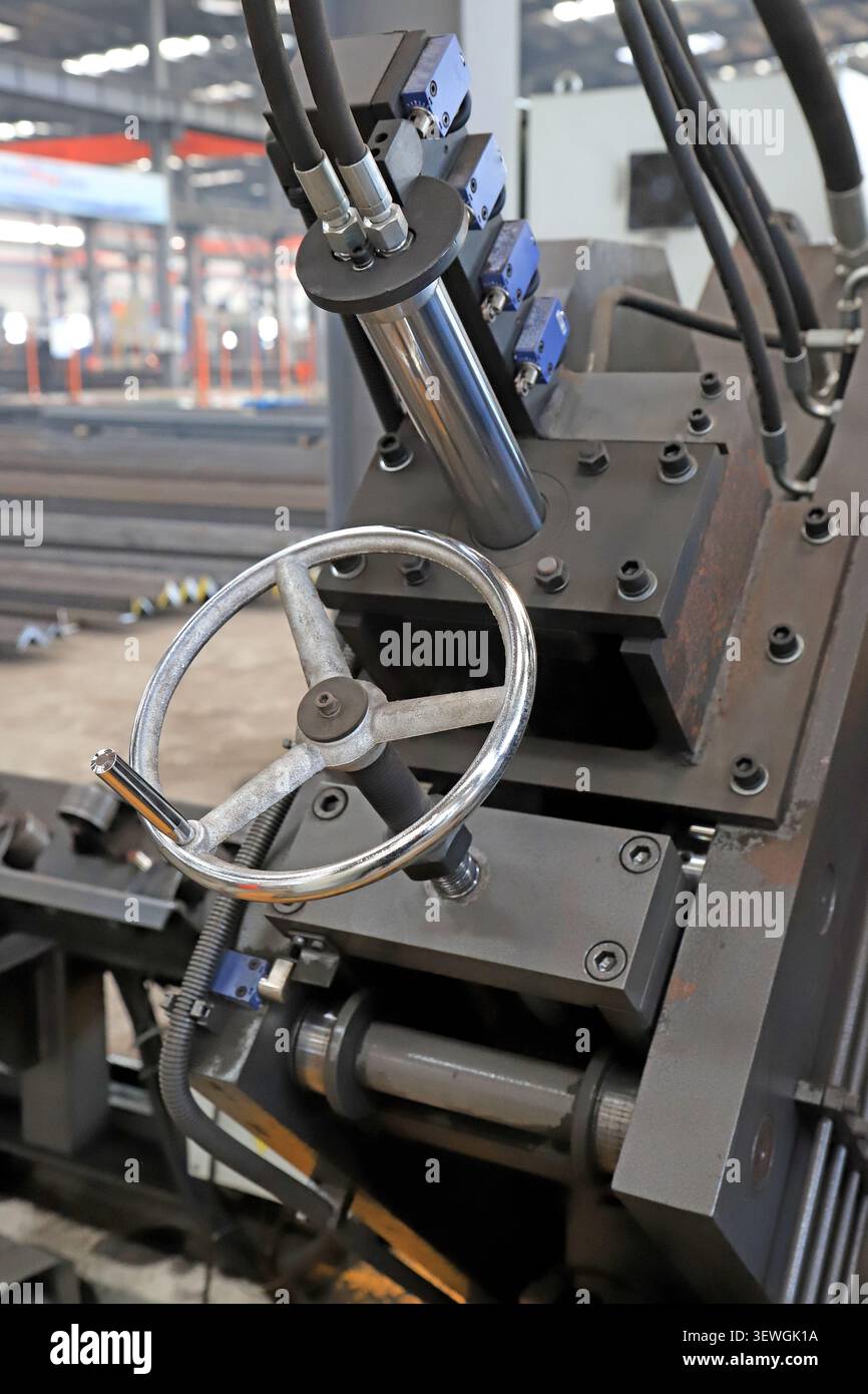 Primo piano ad alta risoluzione di una macchina industriale di precisione, dotata di volante manuale in metallo lucido per la regolazione, abbinato all'impianto idraulico Foto Stock