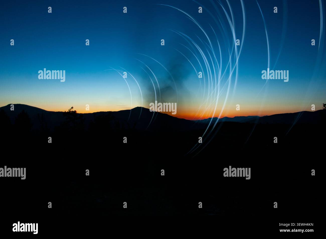 Le stelle si snodano su profili di montagna scuri durante il crepuscolo, mostrando la rotazione della terra Foto Stock