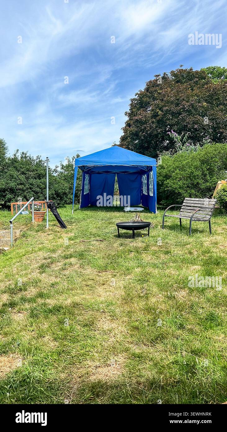 Un gazebo blu allestito in un giardino sul retro nel Regno Unito per fornire riparo e ombra durante un'ondata di caldo - Immagine stock catturata con smartphone