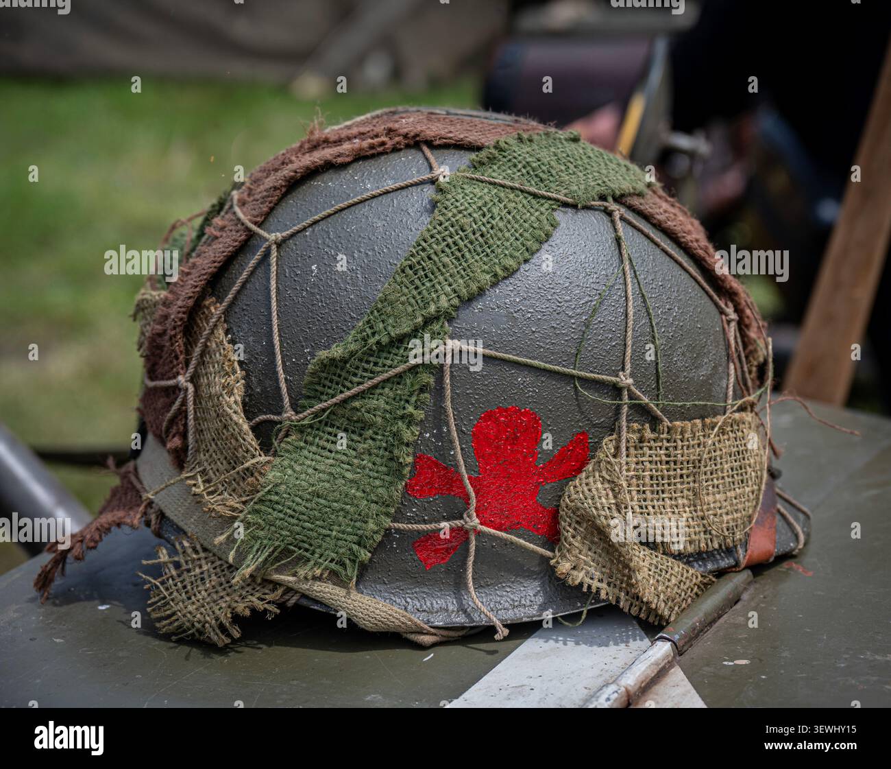 Una replica del casco di fanteria M-1 dell'esercito americano della seconda guerra mondiale, con un distintivo emblema rosso a pannello singolo e decorato con una rete mimetica per nascondere. Foto Stock