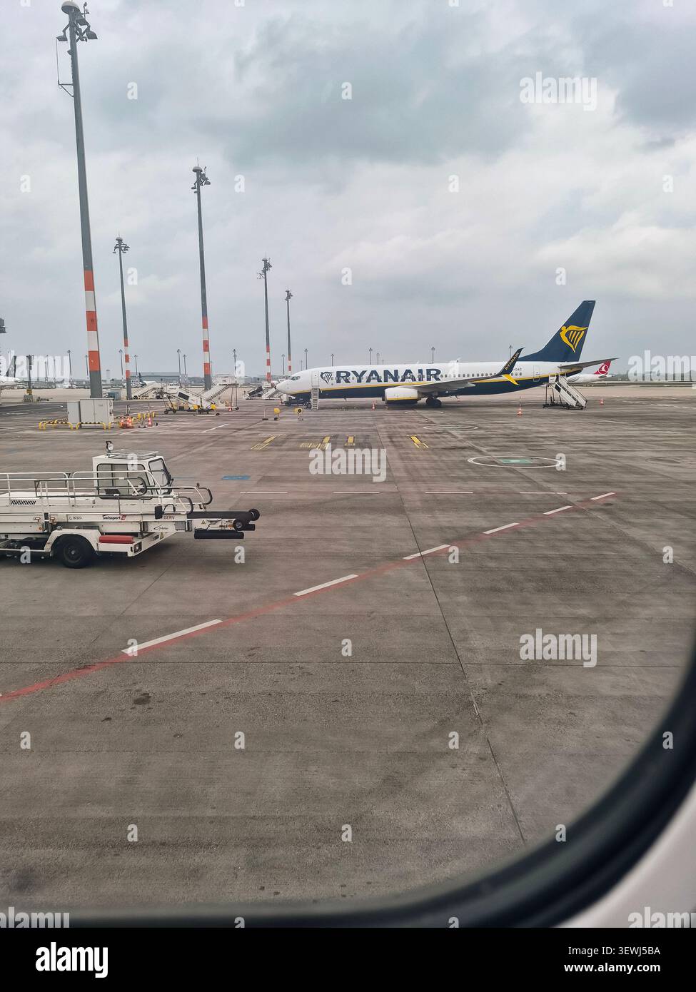L'aereo Ryanair ha parcheggiato sul grembiule dell'aeroporto sotto un cielo nuvoloso Foto Stock