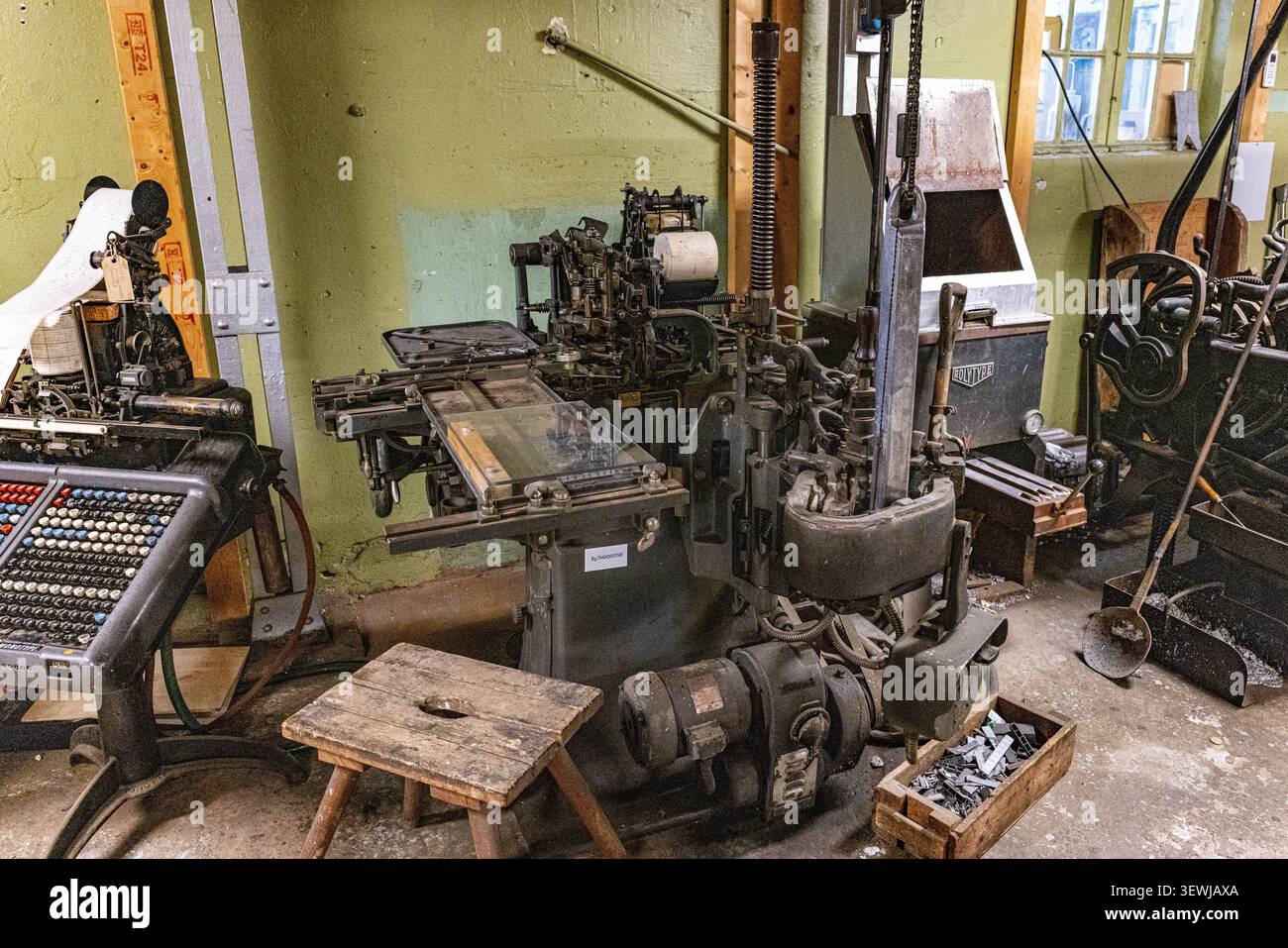 Le vecchie macchine industriali ingombravano un'officina polverosa. Ingranaggi, leve e pannelli di controllo in metallo dominano lo spazio. Gli attrezzi e le casse giacciono sparsi su Foto Stock
