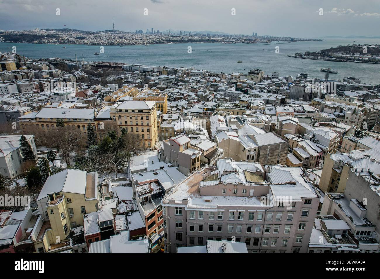 Una vista aerea grandangolare cattura il quartiere storico di Istanbul, con tetti innevati, lo stretto del Bosforo e un paesaggio urbano lontano su una strada di circa Foto Stock