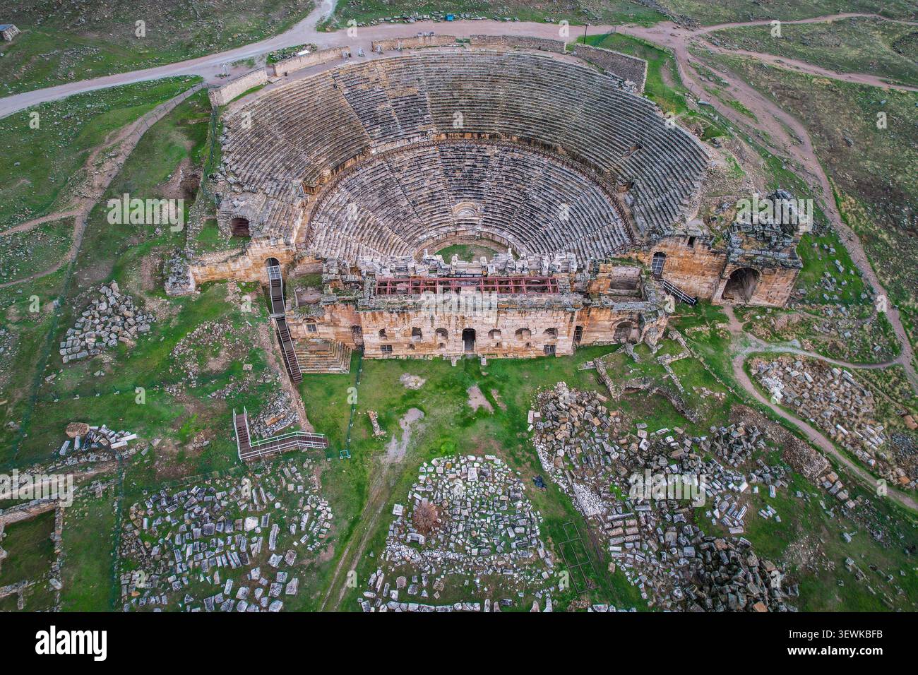 La vista aerea cattura il teatro romano dell'antica città di Hierapolis, situato tra verdi colline e rovine sparse a Pamukkale, Turchia. Questo ben pre Foto Stock