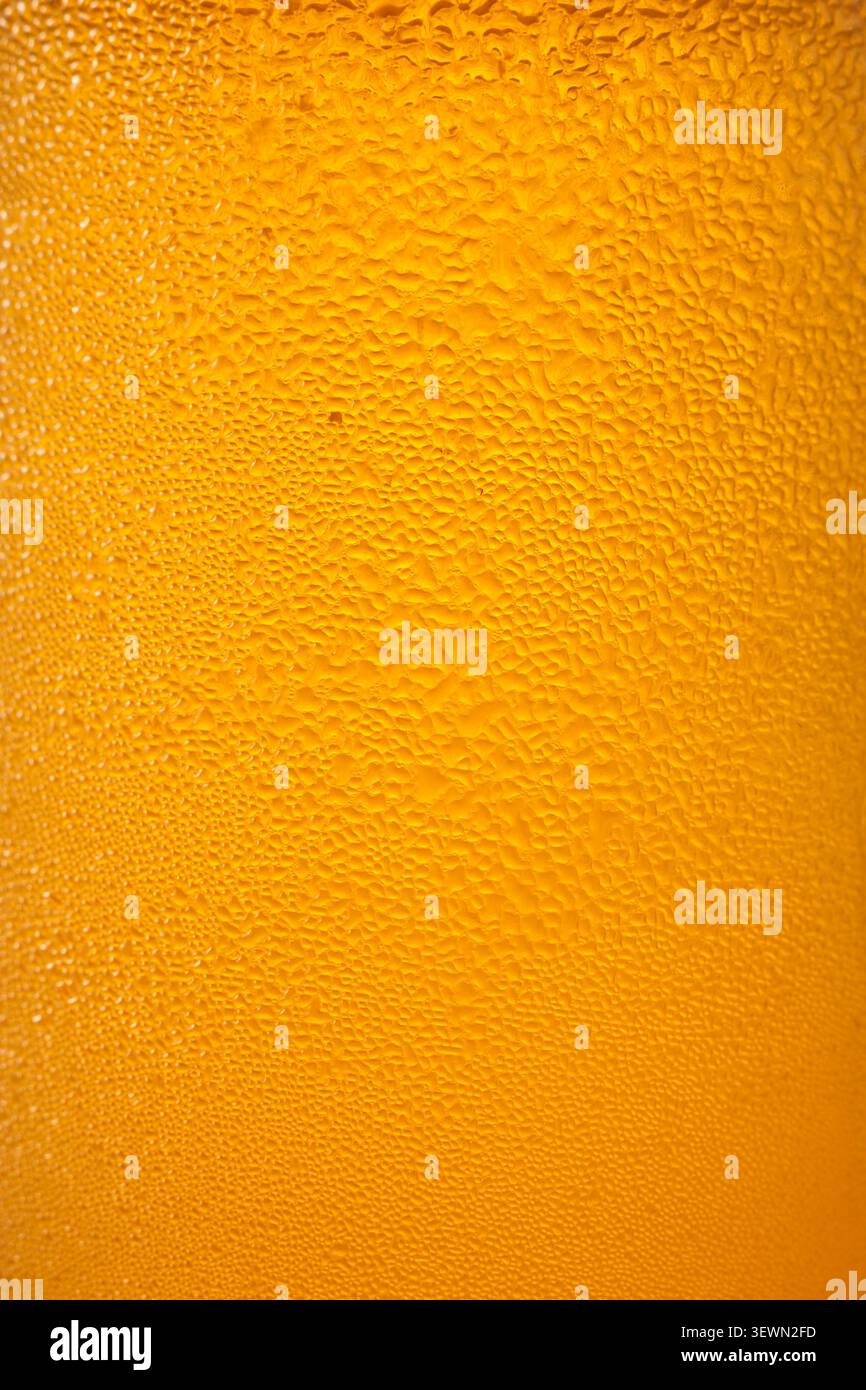 la condensa d'acqua cade sulla superficie del contenitore del liquido arancione freddo in full frame, liquido giallo umido con rugiada fresca, rinfrescante estate Foto Stock