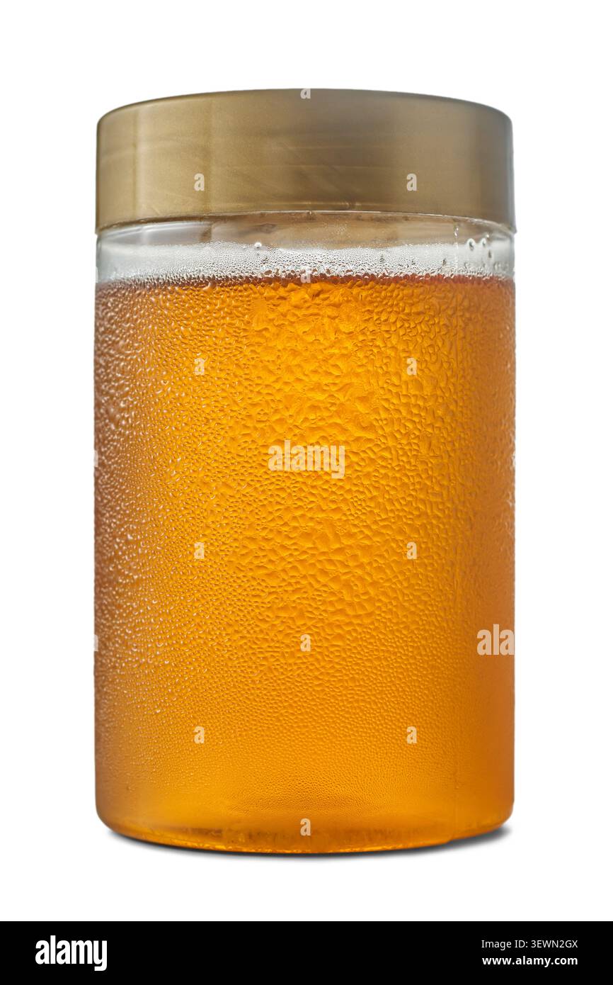 vaso di miele liquido freddo con sfondo bianco isolato dalla condensa, contenitore in plastica ricoperto da gocce d'acqua con coperchio dorato, vista laterale Foto Stock