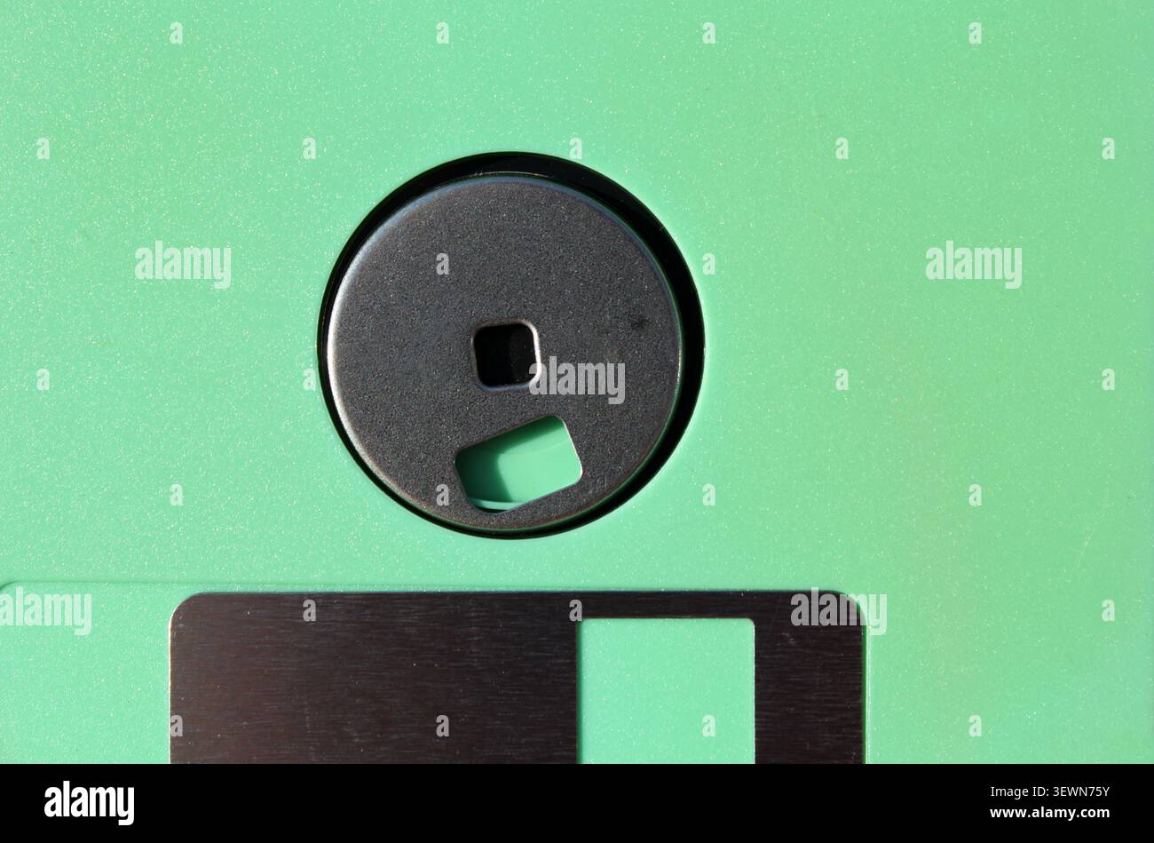 "Macro shot del mozzo centrale in metallo e del cursore su un disco floppy verde da 3,5". Foto Stock
