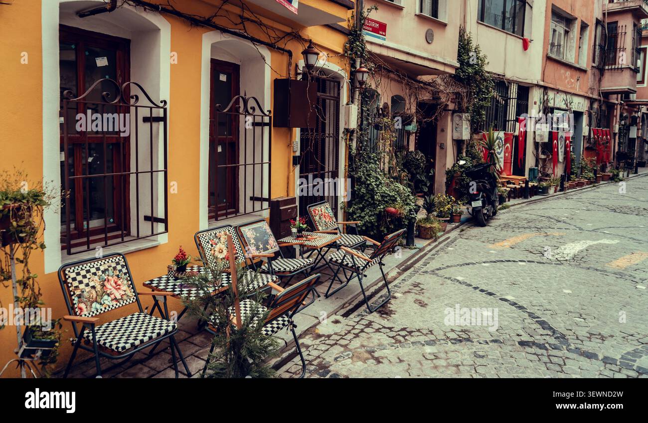 Autentica vita urbana nelle strade di Istanbul, Uno stretto e panoramico vicolo di Istanbul con tradizionali strade acciottolate e affascinanti caffetterie all'aperto Foto Stock
