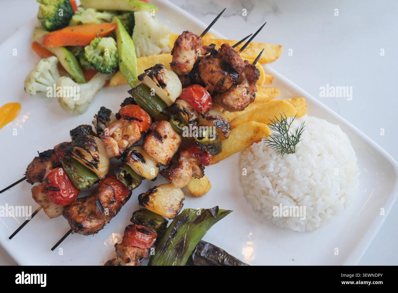 Spiedini di pollo alla griglia serviti con riso e verdure Foto Stock