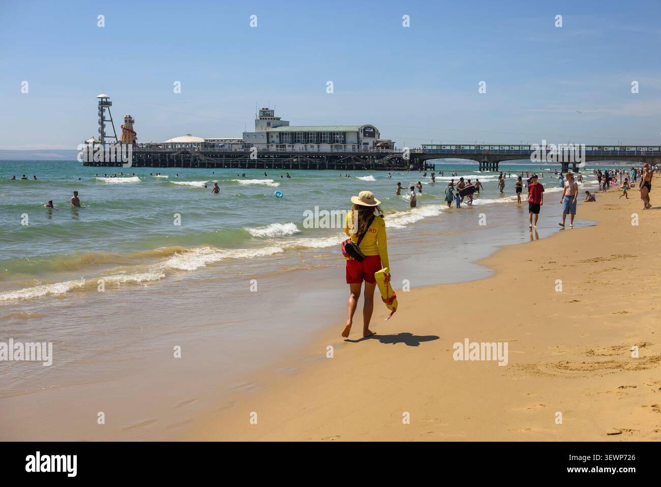 Bournemouth Beach and Pier con persone che nuotano in mare e bagnino di pattuglia, giugno 2026, Regno Unito, ondata di caldo estiva. Foto Stock