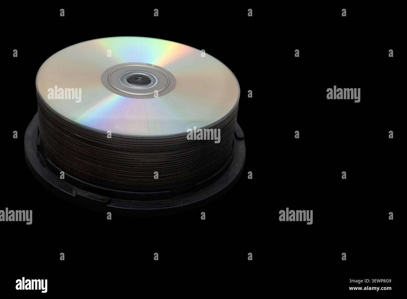 L'immagine mostra una pila di compact disc in una custodia nera. I dischi hanno superfici lucide che riflettono la luce. Lo sfondo è nero fisso. Foto Stock
