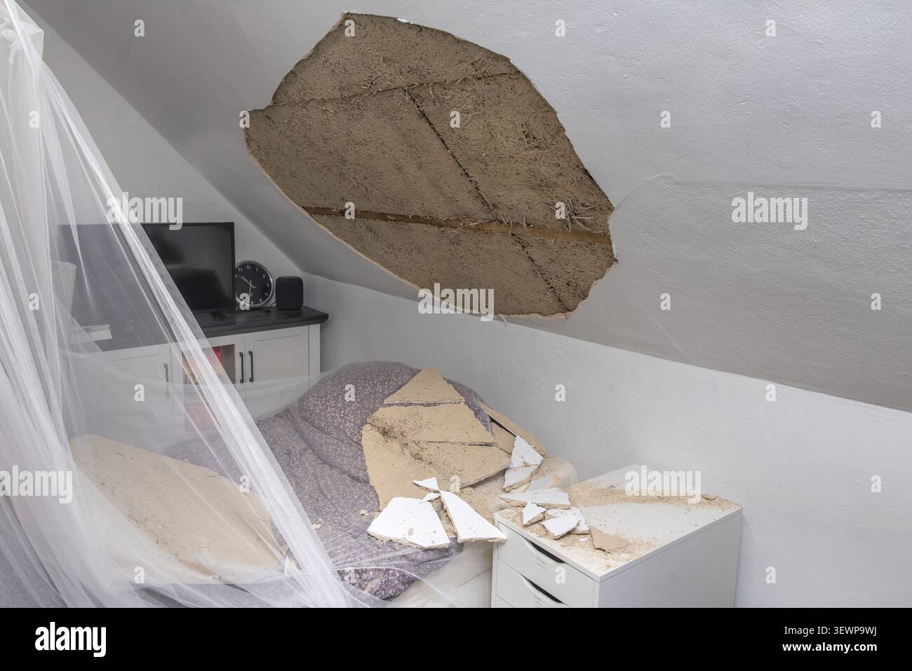 Soffitto della camera da letto crollato con detriti di intonaco e interni danneggiati dopo un guasto strutturale Foto Stock
