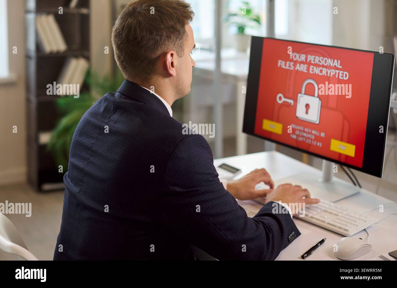 Uomo d'affari che deve affrontare un avviso ransomware sul computer dell'ufficio, rischio di violazione della sicurezza dei dati Foto Stock