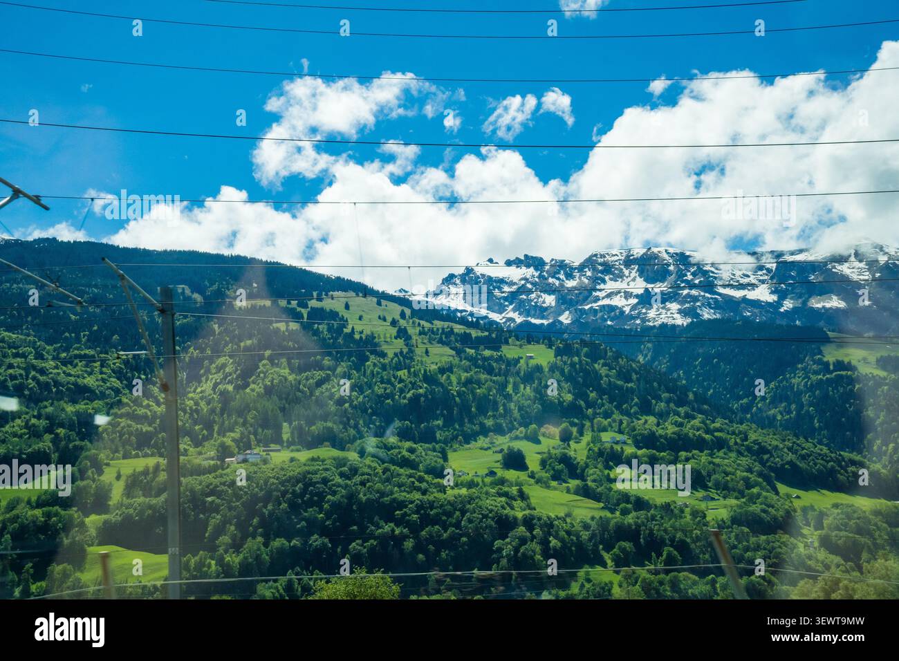 Picco delle Montagne Rocciose alberi verdi cielo blu nuvole bianche campagna svizzera Foto Stock