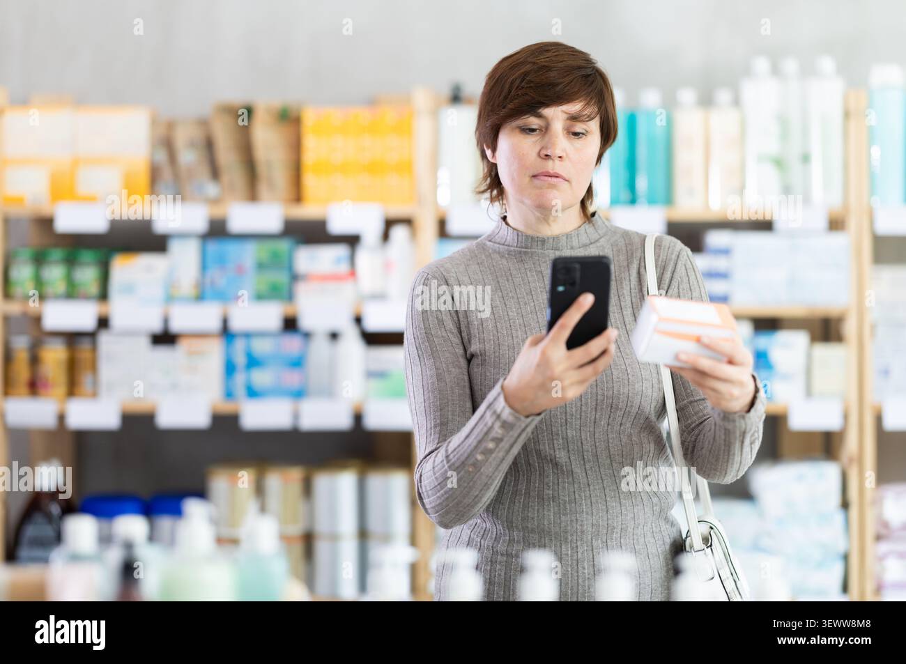 Donna in abiti autunnali scansiona il codice sulla confezione di pillole per controllare la data di scadenza Foto Stock