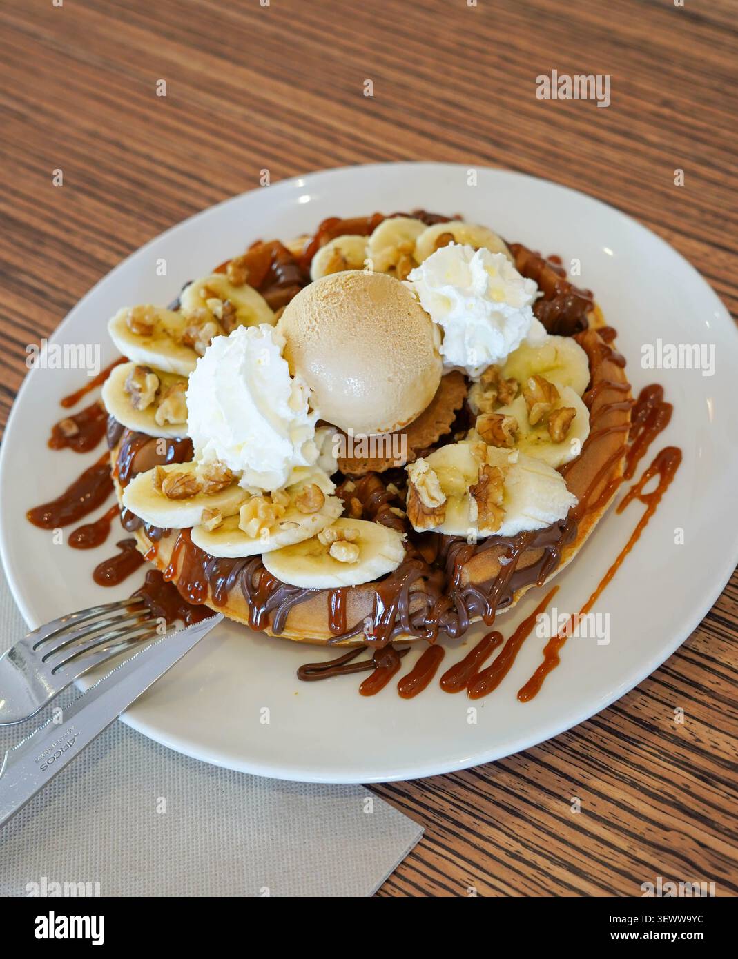 Waffle con banana, noci, salsa al cioccolato, caramello e gelato Foto Stock
